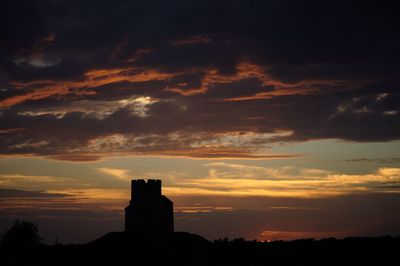 Silhouette built structure against orange sky