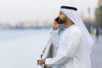 Man in traditional clothing talking over mobile phone while standing outdoors