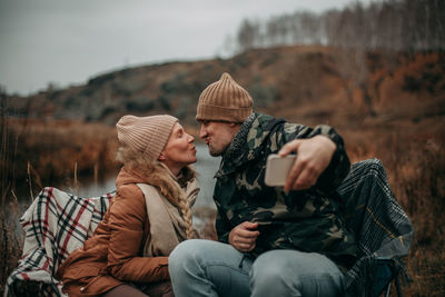 Side view of friends sitting on mountain