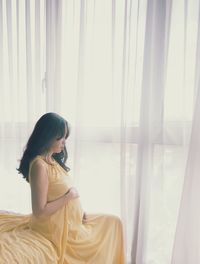 Portrait of young woman sitting on bed at home