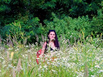 Portrait of a beautiful young woman standing by flowering plants