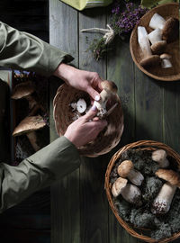 Woman cleans porcini mushrooms in a basket top view harvest of forest