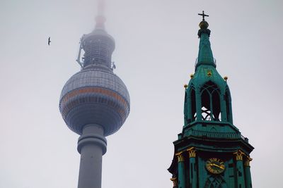 Low angle view of fernsehturm and church against clear sky