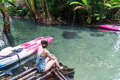 Woman sitting on wooden raft in river