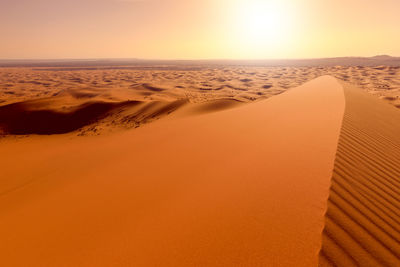 Scenic view of desert against clear sky during sunset