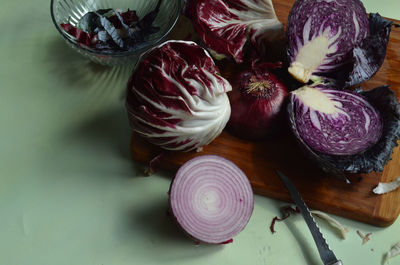 Radicchio, knife, cut red cabbage, red onion, on bamboo cutting board on light green surface