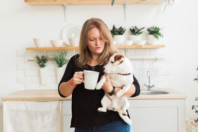 Young woman holding coffee cup at home