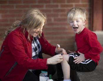 Mother putting bandage on son knee