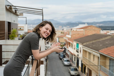 Portrait of smiling young woman standing in balcony