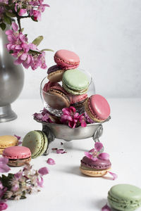 Spring still life with colored macaroons and pink apple tree flowers in a pewter