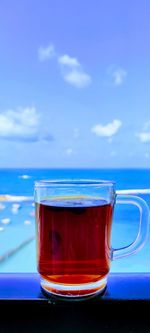 Close-up of tea in glass on table against blue sky