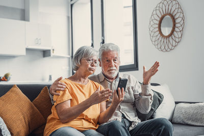 Young woman using mobile phone while sitting at home