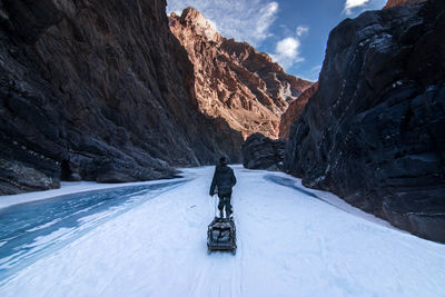 Rear view of person walking on snow covered mountain