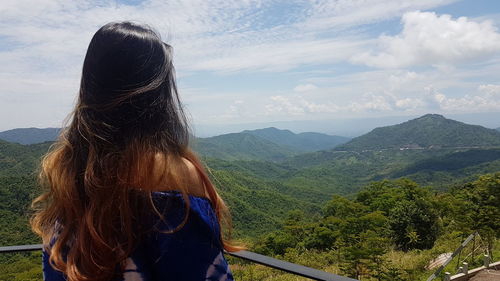 Rear view of woman looking at mountains against sky