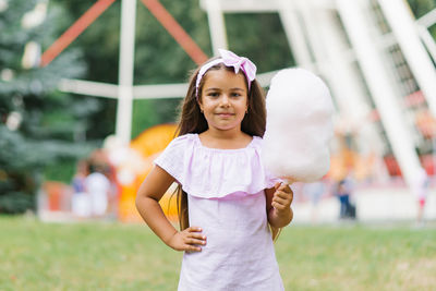 Child girl in an amusement park in the summer eats cotton candy and smiles happily