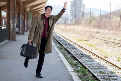 Businessman hailing while standing on platform