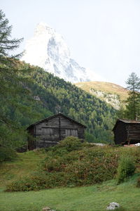 House on field by mountain against sky