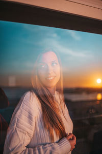 Portrait of smiling young woman against sky during sunset