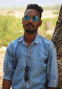 Young man wearing sunglasses standing on field