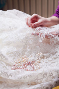 Cropped hands of woman stitching wedding dress