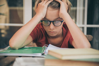 Frustrated boy with head in hands studying