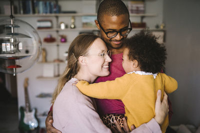 Young parents hugging daughter at home