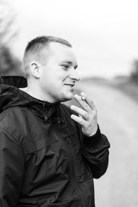 Smiling man smoking cigarette against sky