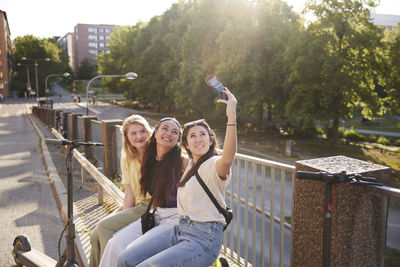 Young female friends spending time together outdoors and taking selfie