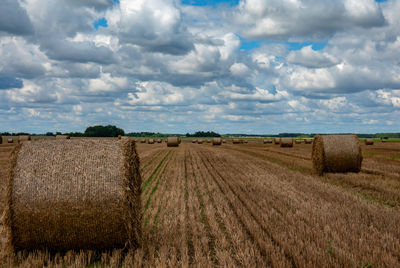 Hay bales on field against sky