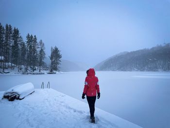 Rear view of woman walking on snow covered landscape