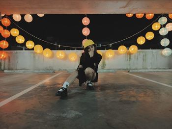 Full length portrait of woman standing against illuminated wall