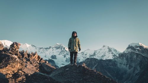 Man standing on snowcapped mountain against sky