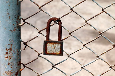 Close-up of rusty padlock on chainlink fence