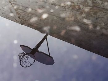 Puddle reflection of basketball hoop against sky