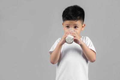 Portrait of boy drinking from glass against white background