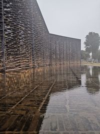 Water fountain by lake in city against sky during monsoon