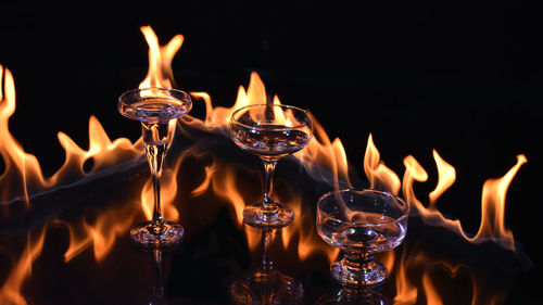 Close-up of lit candles on glass at night