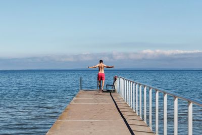 Rear view of man standing on sea against sky