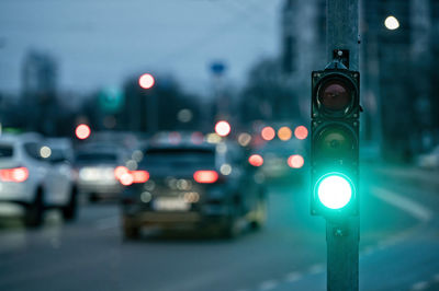 A city crossing with a semaphore on blurred background with cars in the evening streets, green light