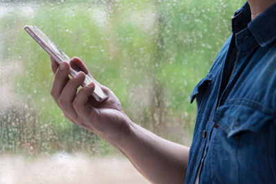 Midsection of man holding mobile phone