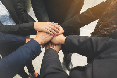 Midsection of colleagues stacking hands in office