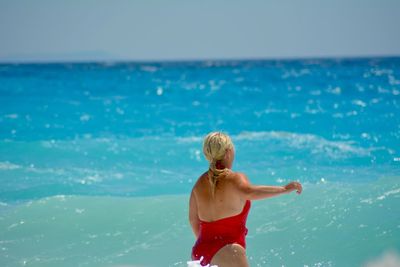 Rear view of woman standing in sea against sky