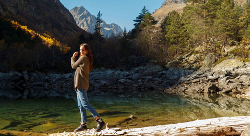 Side view of woman standing on rock against mountain