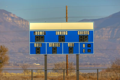 Low angle view of information sign on landscape against sky