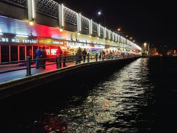 People on illuminated bridge at night