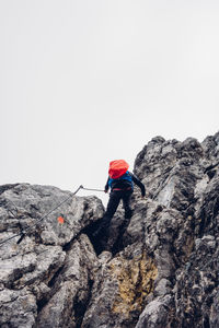 Low angle view of person skiing on cliff against clear sky