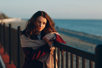 Beautiful young woman by sea against sky