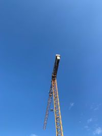 Low angle view of crane against blue sky