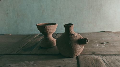 Close-up of vase on table against wall at home