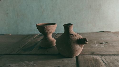 Close-up of vase on table against wall at home